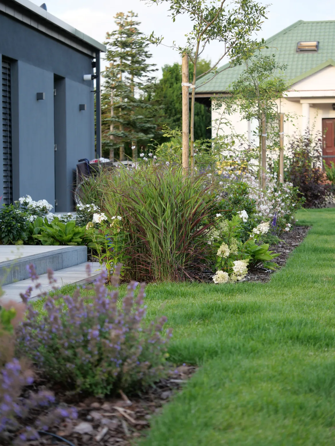 Rabaty bylinowe przy geometrycznym trawniku.