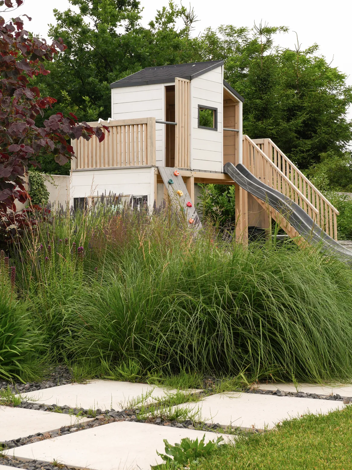 Plac zabaw w ogrodzie rodzinnym, domek Fido w kolorze biało beżowym.