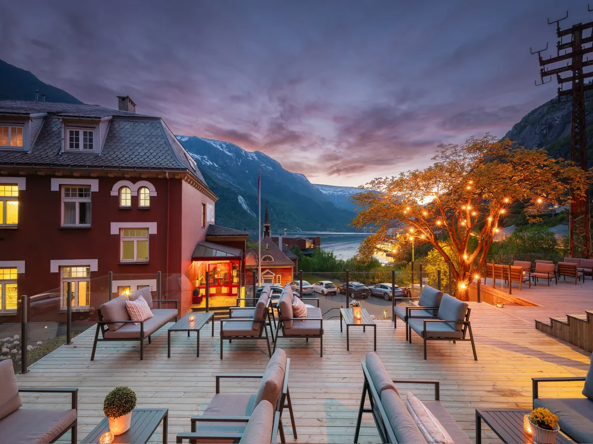 Stoliki i fotele na drewnianym tarasie należące do hotelu.