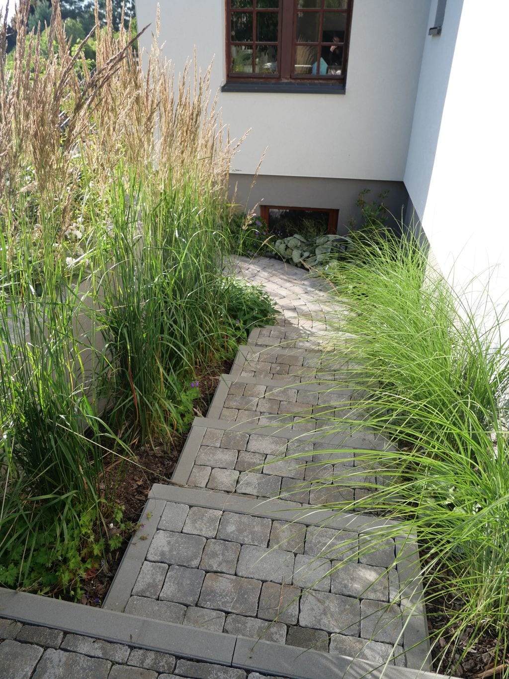 Schody brukowe między poziomami ogrodu otoczone trawami