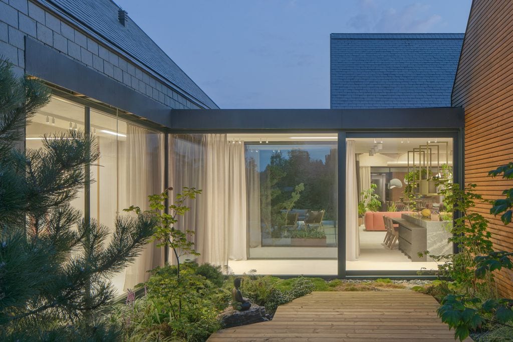 Szklany łącznik między bryłami domu. Mały taras boczny o nieregularnym kształcie nazywany strefą zen. Fot. Piotr Krajewski