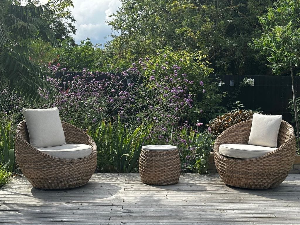 Rattanowe meble tarasowe. W tle byliny.